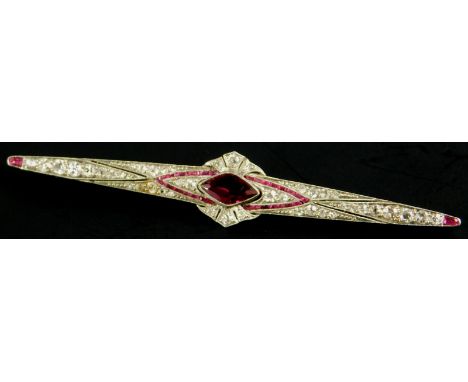 An Art Deco bar brooch, set with central lozenge shaped ruby of 10mm x 6mm, surrounded by pave set diamonds, with baguette ru