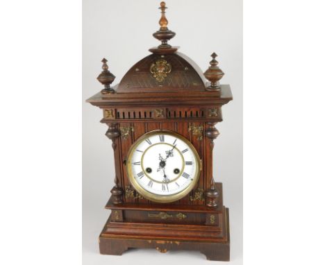 A late 19th/early 20thC oak mantel clock, the hood with turned finials and with brass mounts, the enamel dial with Roman nume