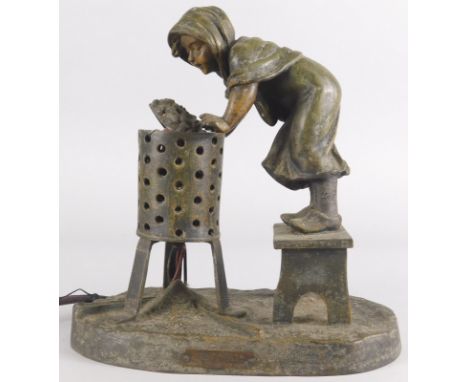 A bronzed metal table lamp, modelled in the form of a lady standing on a stool beside a brazier, signed to base A. De Raniers