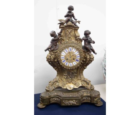 A large 20th Century French metal clock surmounted with cherubs, with enamel and cartouche dial with built-in plinth, strikin