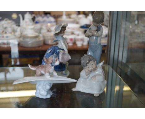 A group of four Lladro figurines to include a dog on a paper plane, girl in a dress holding a floral basket, an angel figure 