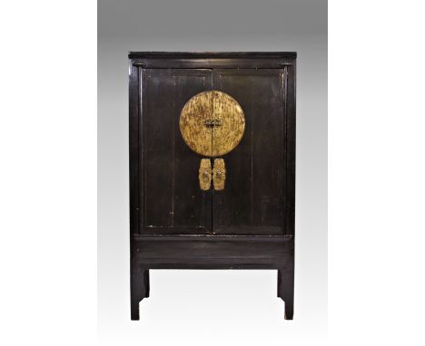 An antique Chinese lacquer wedding cabinet, the two doors with circular patinated brass lock plate and ring handles on shaped