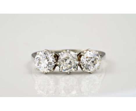 An 18ct white gold and diamond three stone ring, mid-century, the old cushion cut central diamond flanked by a pair of old br