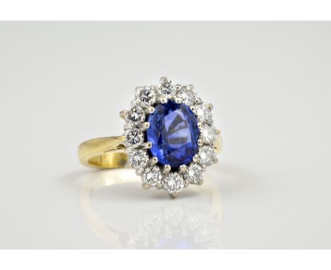 An 18ct white and yellow gold, sapphire and diamond cluster ring, the central oval cut sapphire of good colour, approx. 2.0ct