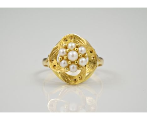 An 18ct yellow gold and seed pearl openwork ring, the floral set seed pearls above a matted quatrefoil openwork setting, ring