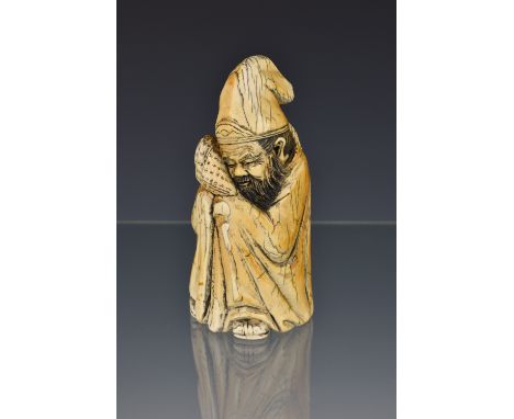 A Chinese carved ivory figure of a scholar, 19th / early 20th century, the bearded, seated figure in robes, holding a loosely