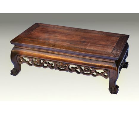 A 19th century Chinese carved hardwood low opium table, the cleated top over a convex frieze and pierced fruit and foliate sc
