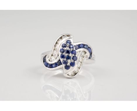 An 18ct white gold, sapphire and diamond swirl set ring, the central leaf pavé set with round cut sapphires, within a swirl o