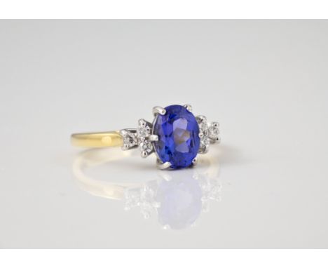 An 18ct gold, Tanzanite and diamond ring, the central oval cut Tanzanite flanked by trios of brilliant cut diamonds, ring siz