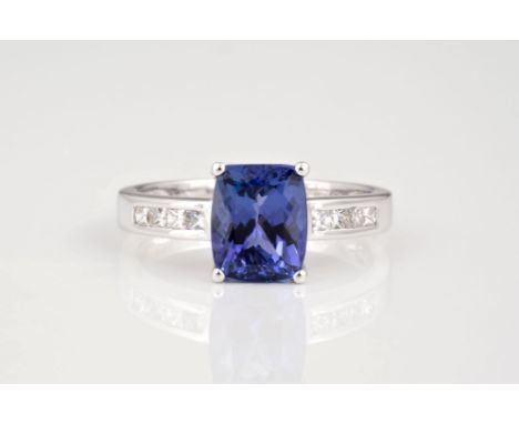 An 18ct white gold Tanzanite and diamond ring, the cushion cut 3.66ct Tanzanite over channel set shoulders with princess cut 