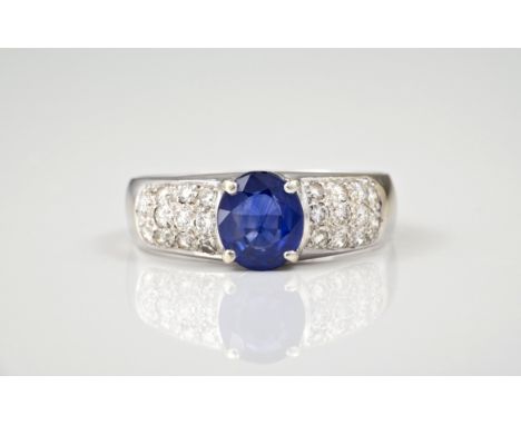 An 18ct white gold, sapphire and diamond ring, the central oval cut sapphire over shoulders pavé set with brilliant cut diamo