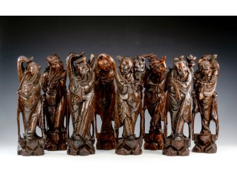 A 19th century set of the Eight Daoist Immortals carved in Chinese hardwood, the robes of each finely inlaid in silver wire w