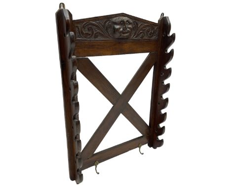 Victorian oak wall hanging whip or stick rack, sloped arch pediment carved with central grotesque mask with extended scrollin