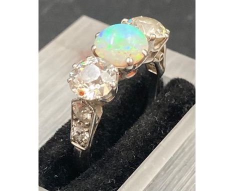 A white opal and diamond three stone ring mounted in platinum. Central opal weighs approx 1 ct, diamonds weighing approx 0.80