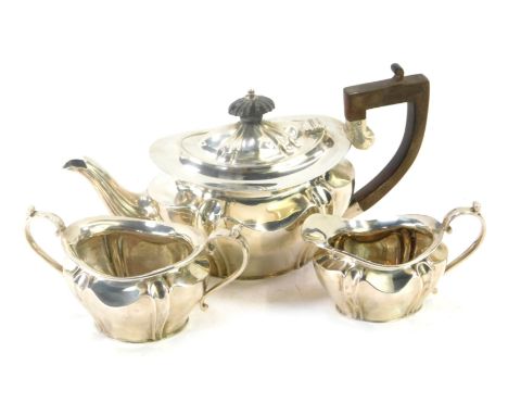 A George V silver three piece tea set, comprising teapot, milk jug, sugar bowl, with fluted body, and ebonised handle, Sheffi