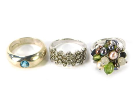 Three dress rings, comprising a silver and cz cluster ring, a silver multi stone dress ring, and a silver and blue topaz set 