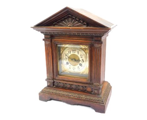 A late 19thC German oak cased mantel clock, the brass square dial with foliate spandrels, circular silvered chapter ring bear