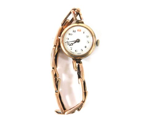 An early 20thC lady's 9ct gold wristwatch, with a circular watch head, with white enamel numeric dial with gold markers, blac