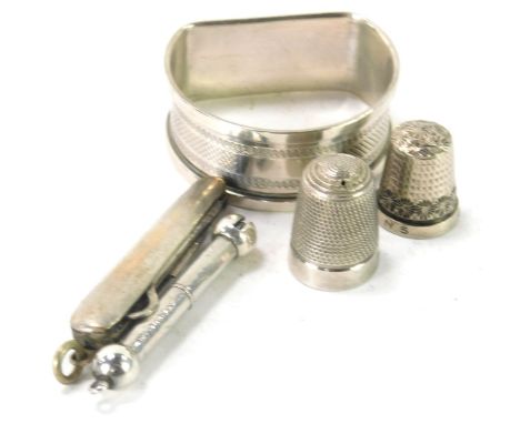 Silver trinkets, comprising two silver thimbles, a silver D shaped napkin ring, silver whistle, and a stainless steel penknif