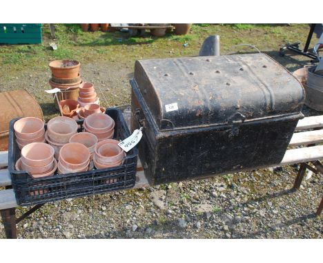 A metal trunk and tray of terracotta flower pots.
