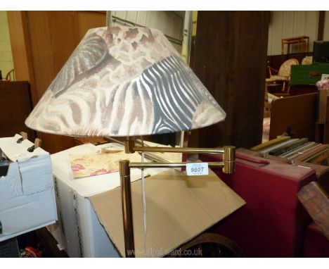 A gold coloured standard lamp with shade and articulated top.