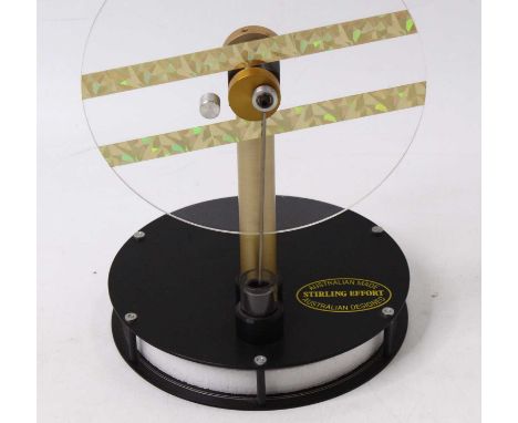 An Australian-made Stirling engine, comprising a polystyrene cylinder head, and a plastic flywheel, mounted on a metal base. 