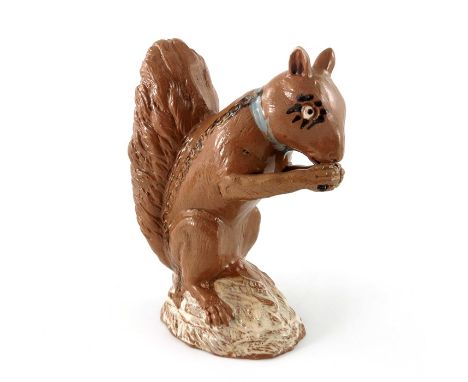 An Astbury type 18th Century Staffordshire pottery figure of a squirrel nibbling a nut, with  stylised lashes and blue collar