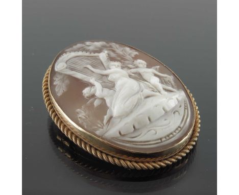 A late Victorian oval cameo brooch depicting harp player and putti, within a wire twist frame.