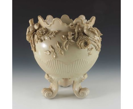 A Belleek florally encrusted jardiniere, ovoid form, supported on three scroll and shell moulded bracket feet, the body half 