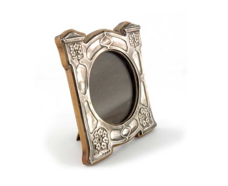 An Arts and Crafts silver photo frame, J Aitkin and Son, Birmingham 1908, the circular glass within a wooden backed embossed 