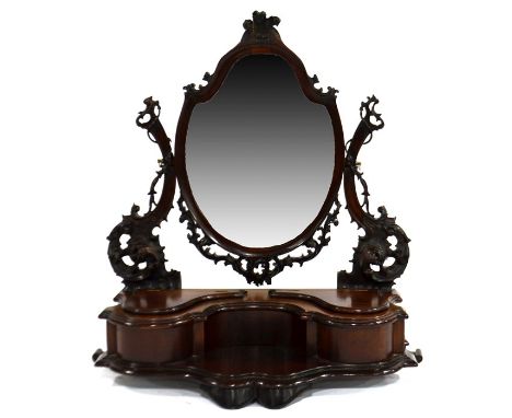 A Victorian carved mahogany swing toilet mirror, the shield shaped bevelled glass with Prince of Wales feathers and open garl