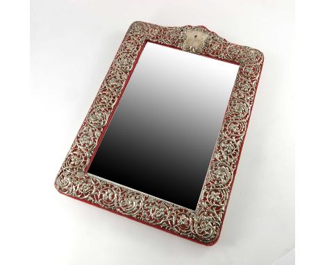 An Edwardian silver easel back mirror, Henry Matthews, Chester 1905, embossed and reticulated foliate scroll design on a red 