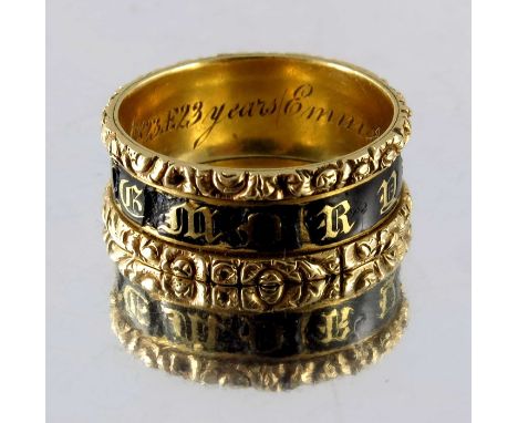 A George IV gold and enamelled mourning ring, the central black enamel band with Gothic letters, between relief moulded folia