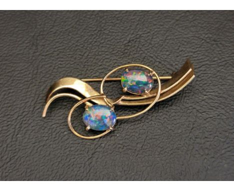 OPAL TRIPLET SET NINE CARAT GOLD BROOCHthe two opal triplets in wavy scroll setting, 3.8cm long and approximately 2.6 grams 