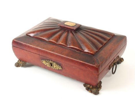 A Regency grained red leather sarcophagus form sewing box, the convex sides below a reeded lid panel rising to a gilt tablet,