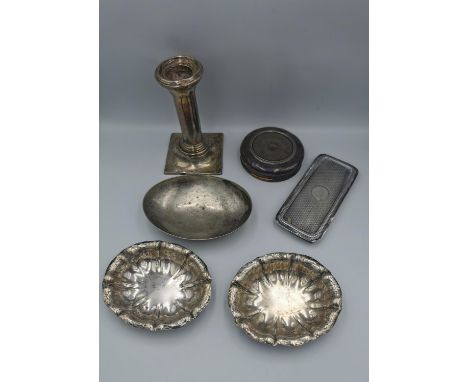 A collection of silver, including a weighted silver candle stick, an oval dish with engraved monogram, two silver lids and tw