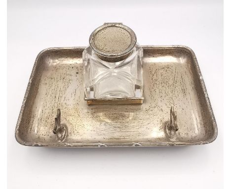 A sterling silver inkwell and pen stand with ribbon detailing to the edge, button feet and shield form pen holder. Removable 