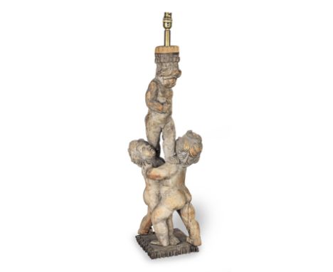 A pine figural carvingFitted as a lamp, of three cavorting putti, one atop the shoulders of the other two, on a square base w