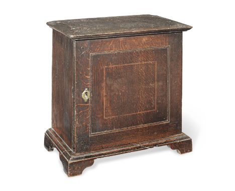 A George I oak table-top spice cupboard, circa 1715Having a one-piece top with shallow chamfered-edge, a single flush-panelle