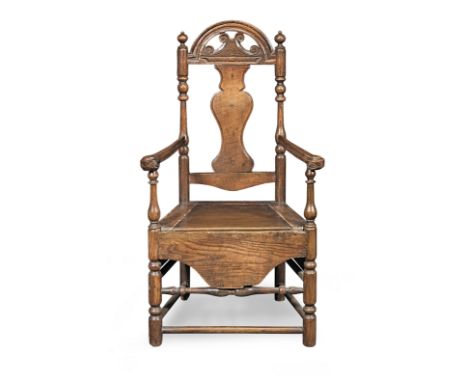 An early 18th century walnut, fruitwood and ash commode open armchair, Welsh, circa 1725Having a solid vase-shaped splat, an 