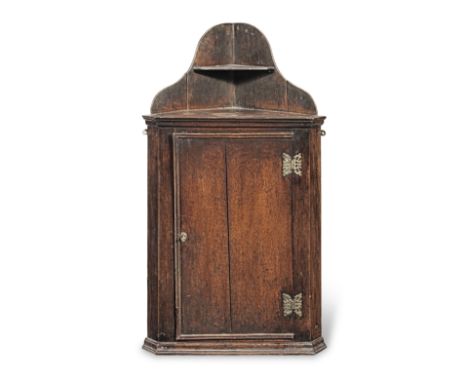 A George III oak hanging corner cupboard, circa 1760The integral raised superstructure with single shelf, atop a boarded door