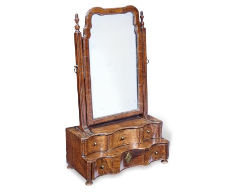 A George I walnut-veneered toilet mirror, circa 1725Having a rare two-tier serpentine shaped base, fitted with four drawers, 