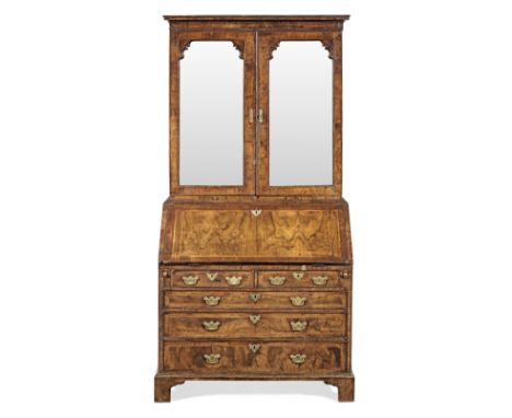 A George II figured walnut and featherbanded bureau cabinet, circa 1740Having a cavetto-moulded cornice, a pair of mirror-pan