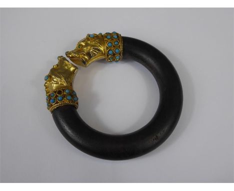 A Wooden Bangle, with gilded dog-head finials set with turquoise.&nbsp;