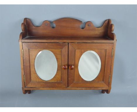 A Small Rectangular Pine Wall Cupboard, with oval mirrored panels to the two doors and a top half-shelf to the interior, appr