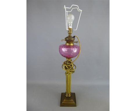 A Converted Oil Lamp, cranberry oil vessel, approx 79 cms high with cream shade.&nbsp;