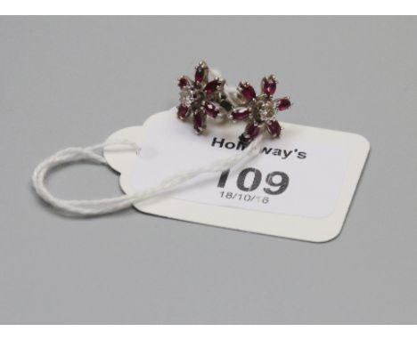 A pair of ruby and diamond flowerhead cluster earrings, within central brilliant cut diamonds and oval cut ruby petals