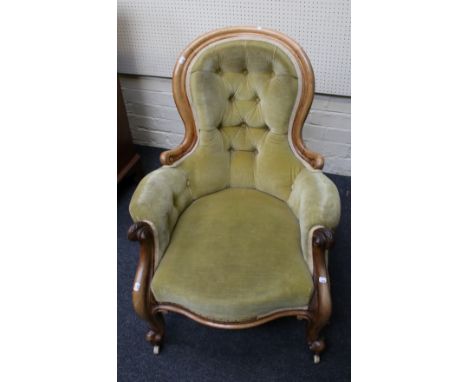 A Victorian walnut framed olive green button plush upholstered spoon back parlour armchair, with leaf carved scrolled arms, s