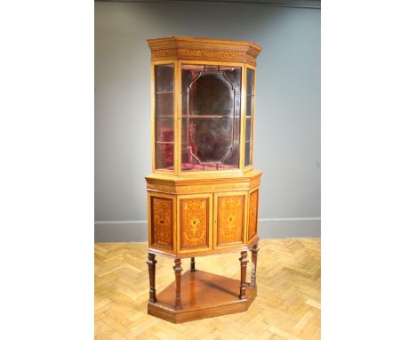 An Edwardian satinwood, mahogany crossbanded marquetry inlaid and strung corner vitrine, having a moulded and dentil cornice 