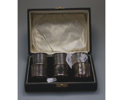 A cased set of six silver serviette rings, each with wavy engine turned bands around a vacant circular cartouche, Chester 192